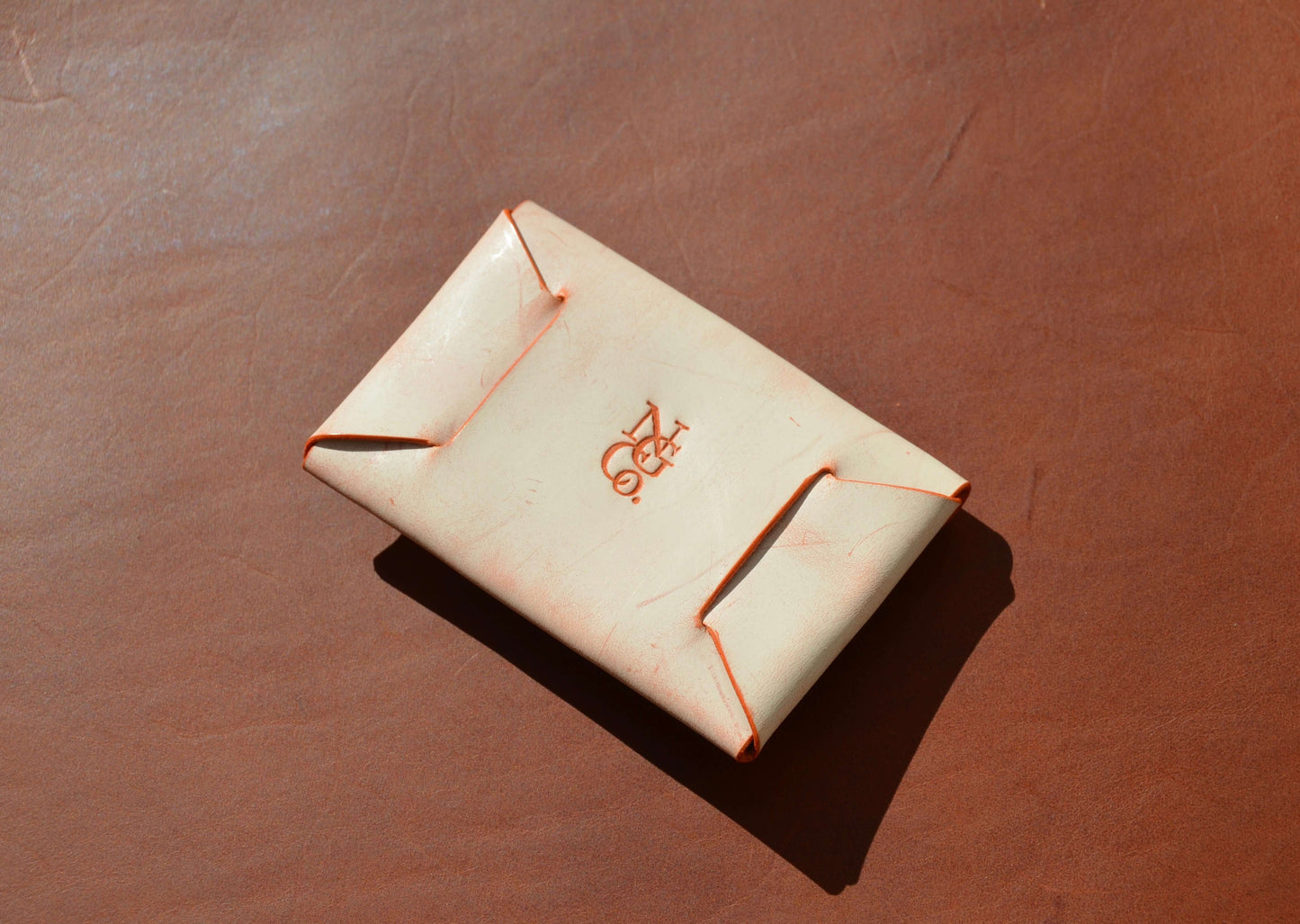Stitchless Handmade Leather Wallet - Made in USA on orange leather surface.