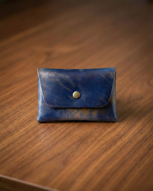Shell Cordovan Stitchless handmade leather wallet in blue on wooden surface.